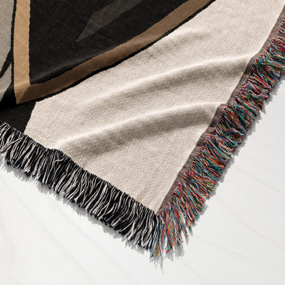 Tan blanket with colorful fringe and geometric pattern, folded.