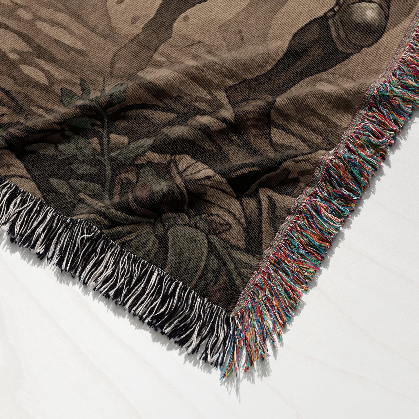 Woven blanket with fringe, featuring a dark, abstract pattern.
