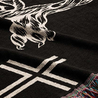 Black knitted throw blanket with white skull and crossbones graphic and fringe.