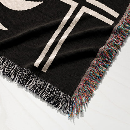 Black throw blanket with white graphic detail and multicolored fringed edge.