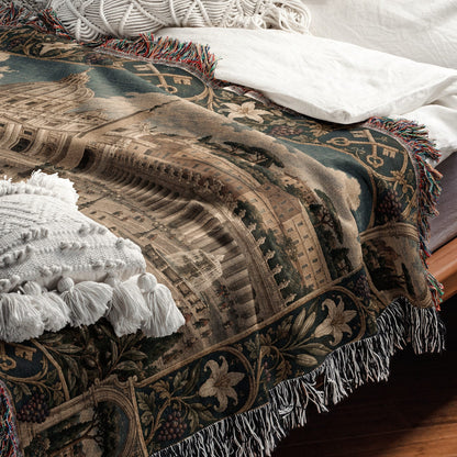 A woven tapestry throw blanket with an architectural scene and fringe, draped over a bed.