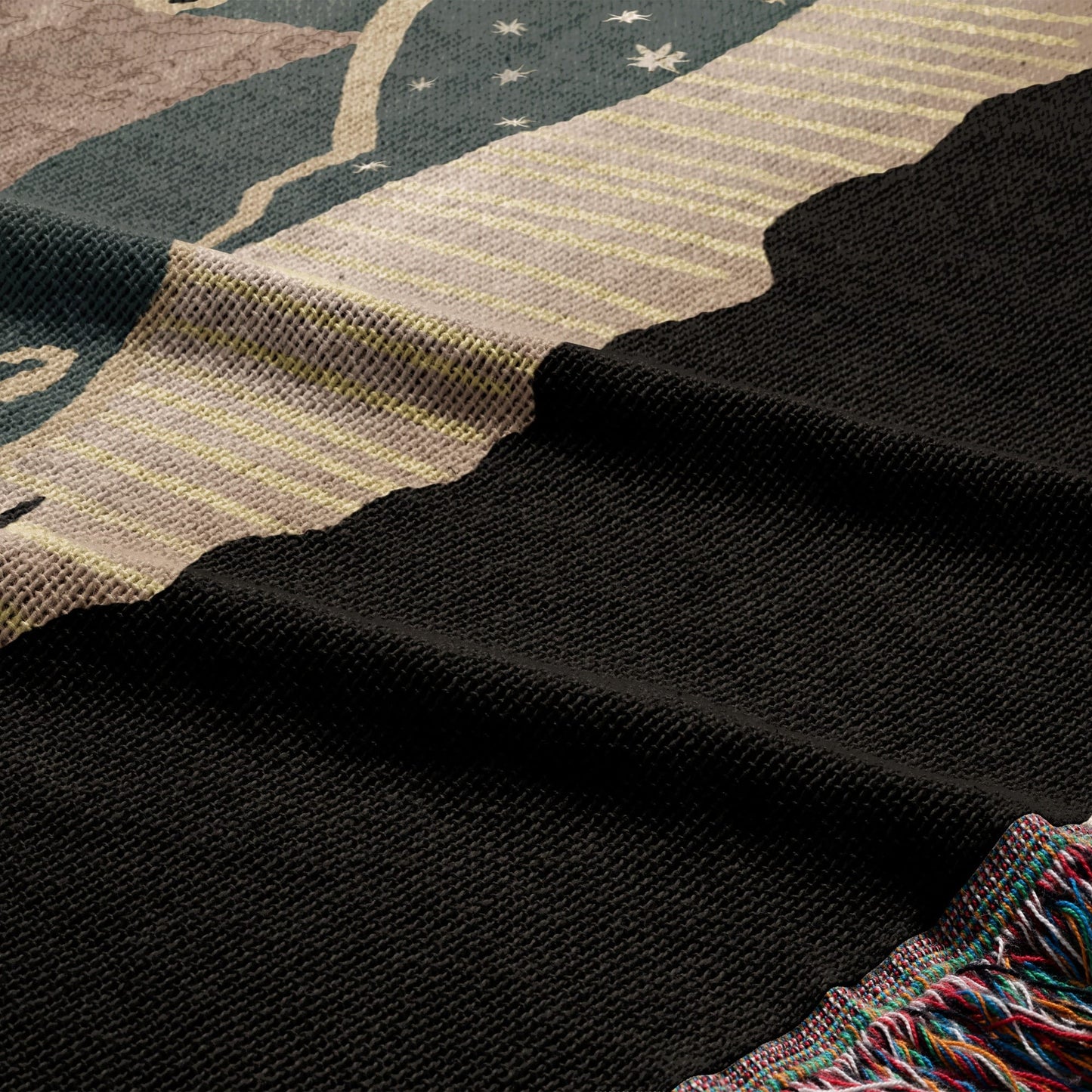 Black woven blanket with a star pattern and colorful fringe detail.
