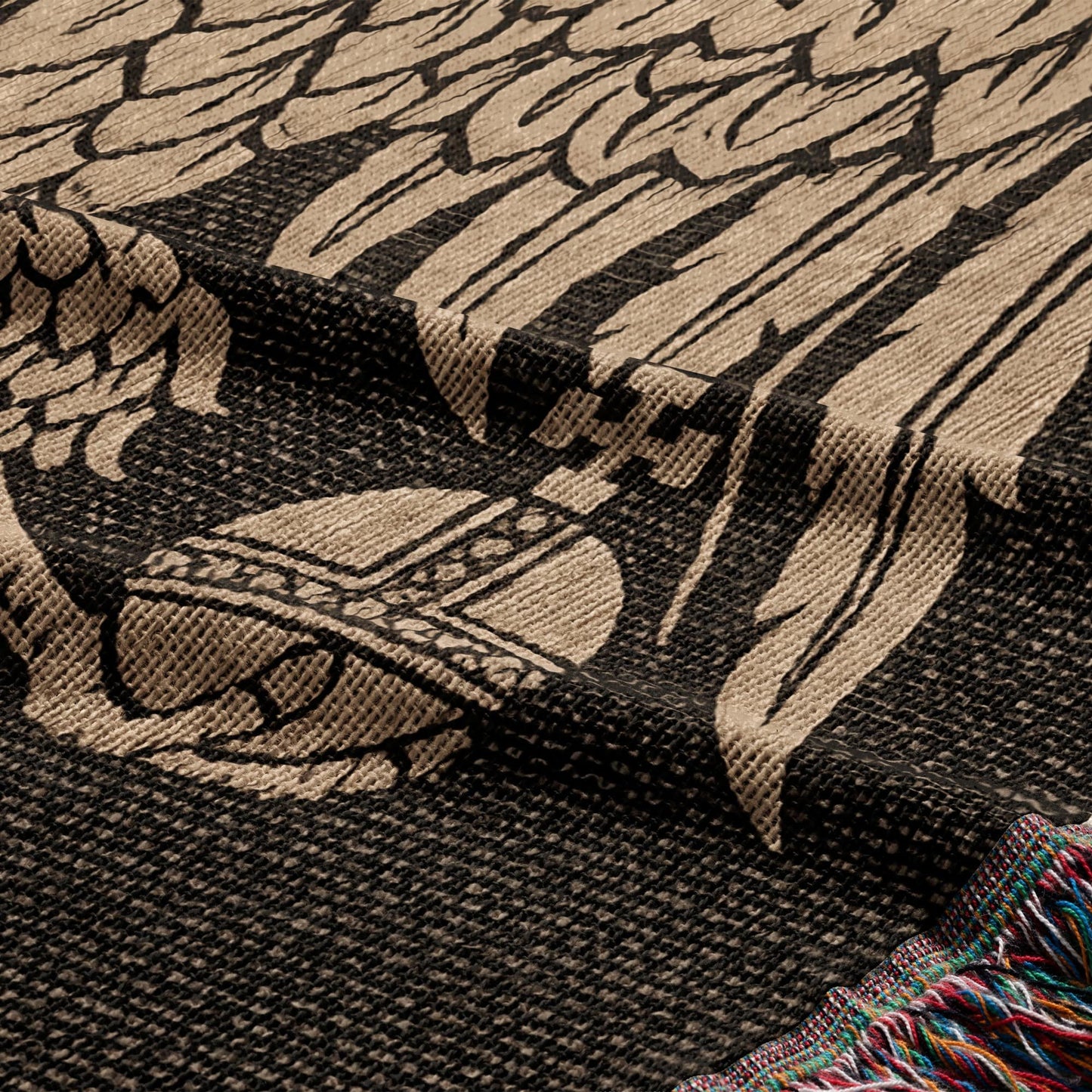 Close-up of a woven blanket with a detailed crest pattern and colorful fringed edge.