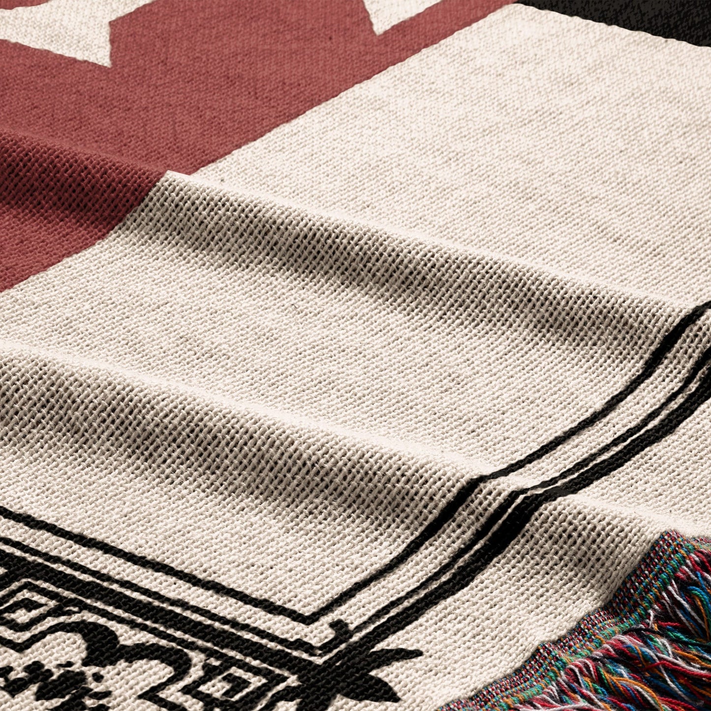 Close-up of a woven blanket with red, cream, and black geometric patterns.