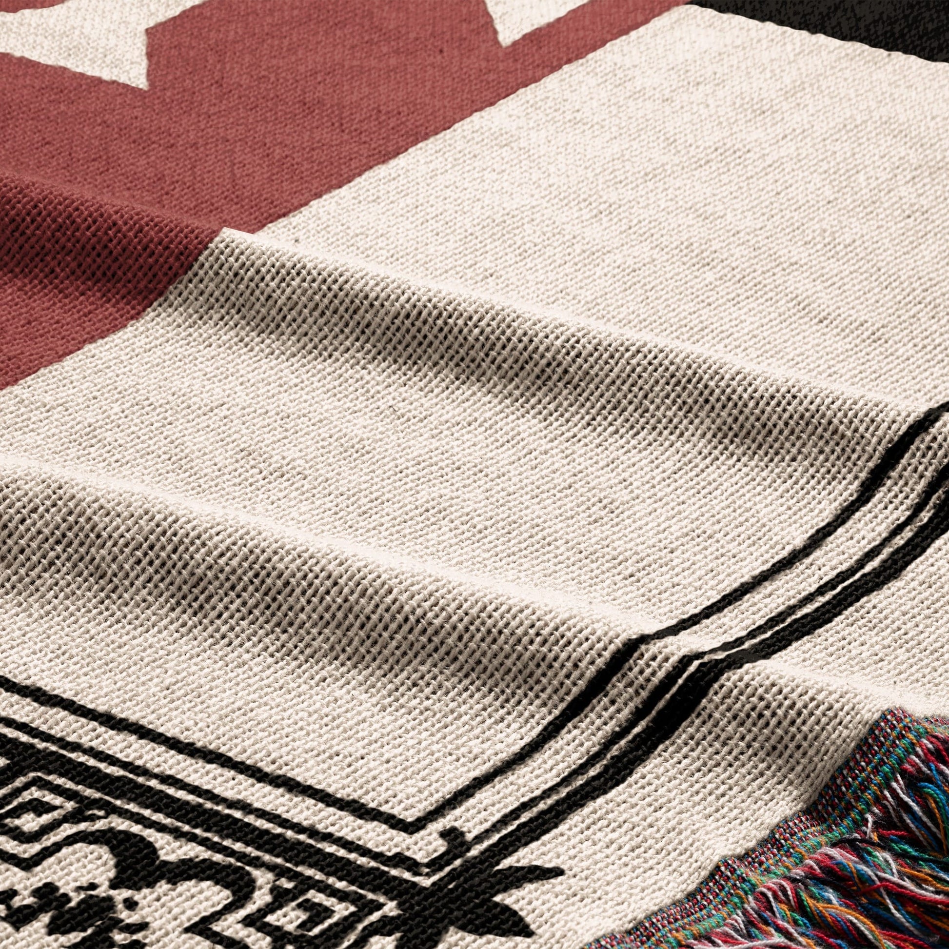 Close-up of a woven blanket with red, cream, and black geometric patterns.