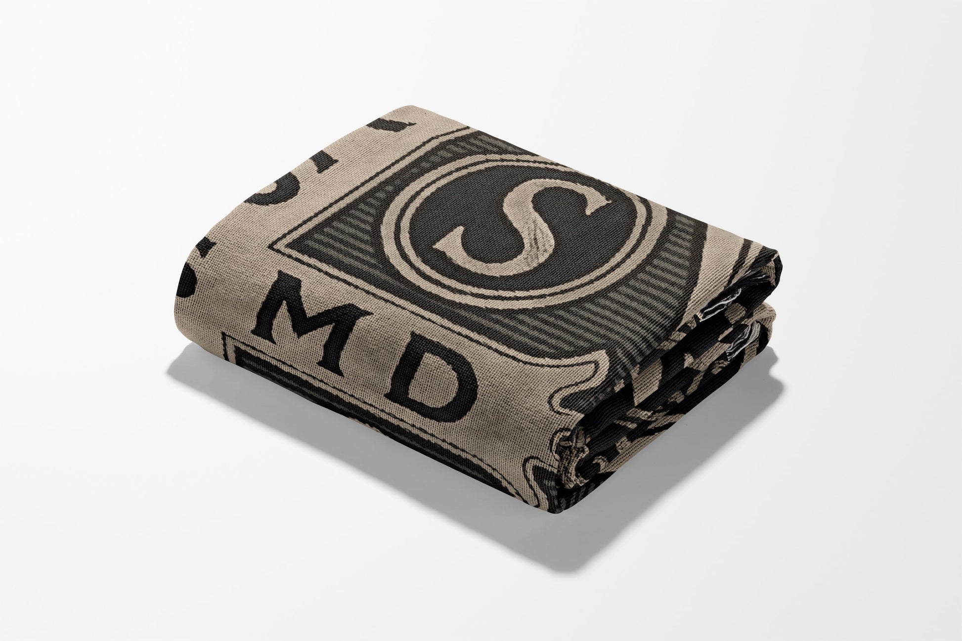 Folded blanket with a dollar bill design, featuring the letter S and MD.