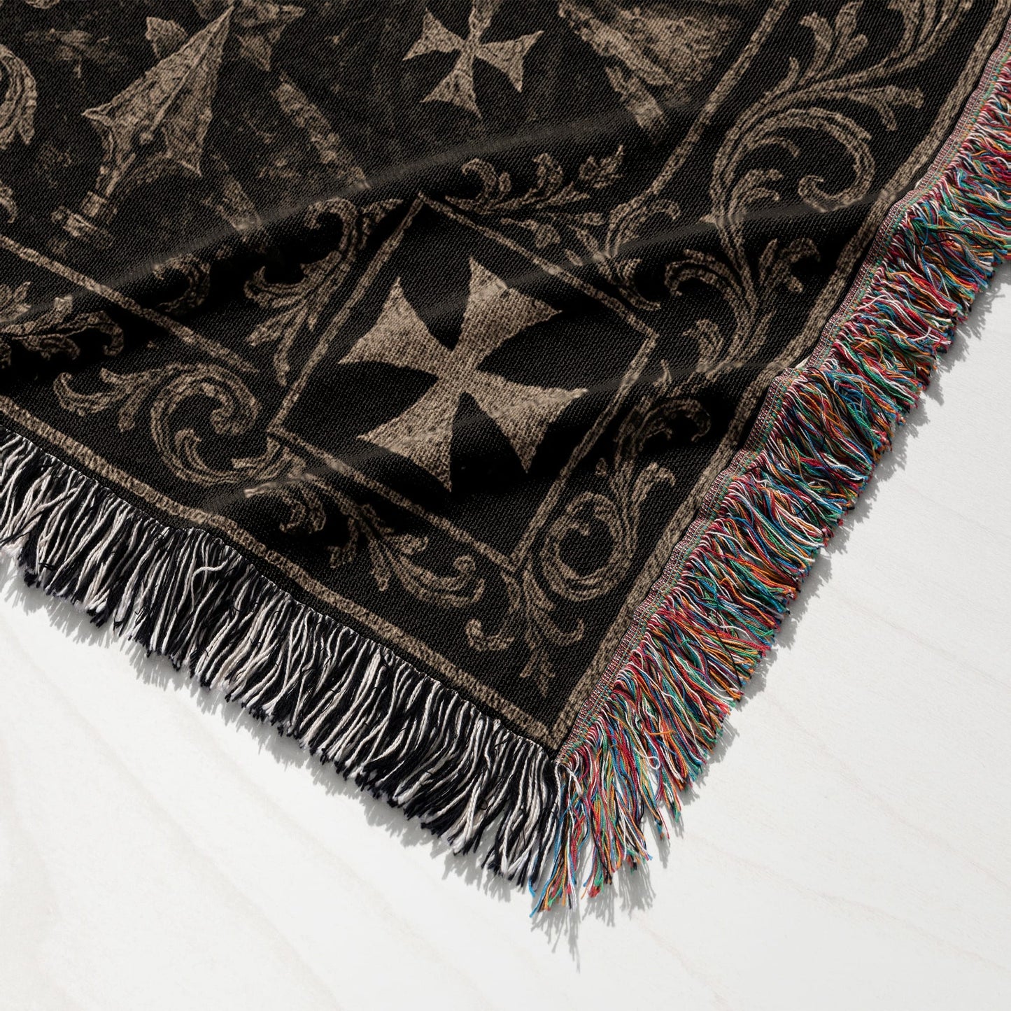 Dark patterned throw blanket with tasseled edges, featuring geometric crosses.