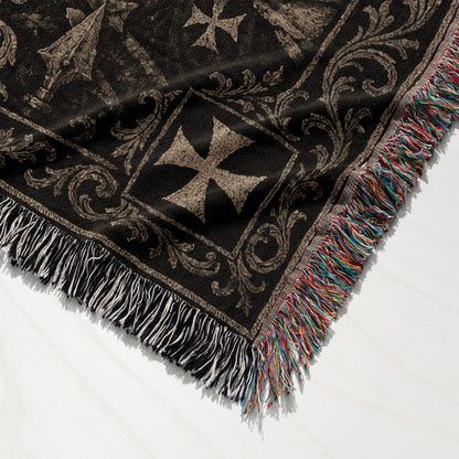 Dark patterned throw blanket with tasseled edges, featuring geometric crosses.