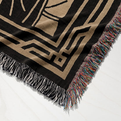 Black and tan geometric pattern woven blanket with tasseled edges.