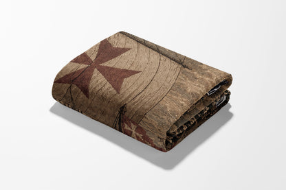 Folded tapestry with red cross pattern on wooden background.
