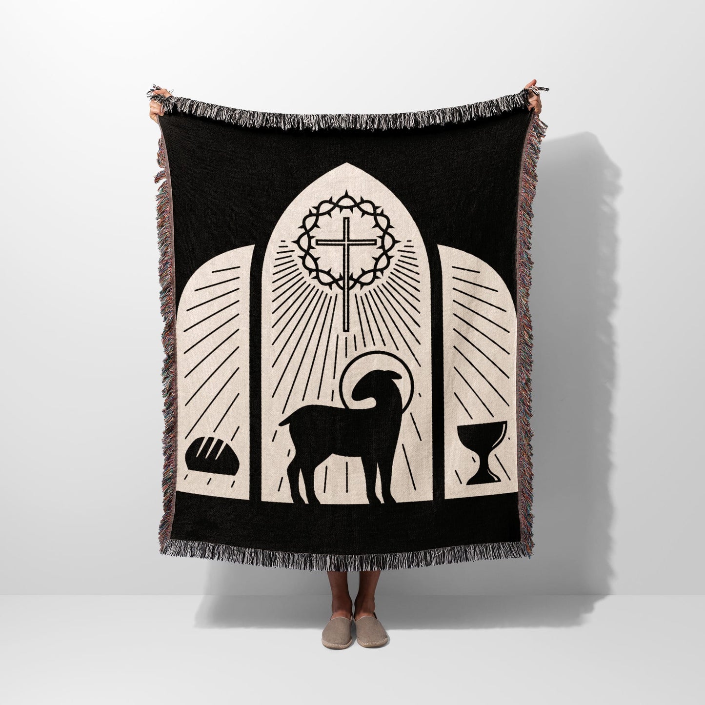 Black woven blanket with religious symbols: lamb, cross, bread, and chalice.