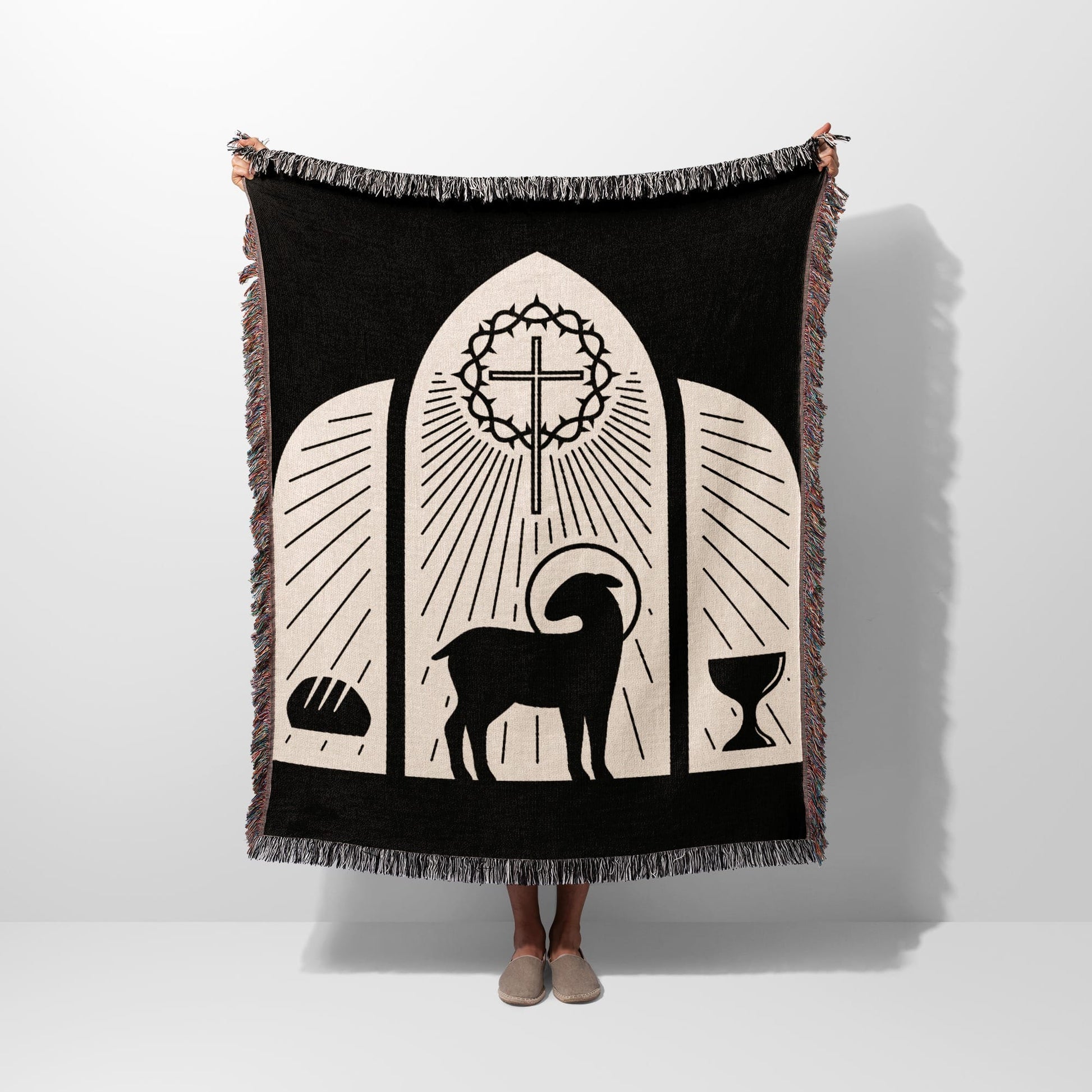 Black woven blanket with religious symbols: lamb, cross, bread, and chalice.