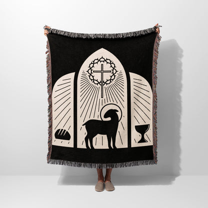 Black woven blanket with religious symbols: lamb, cross, bread, and chalice.