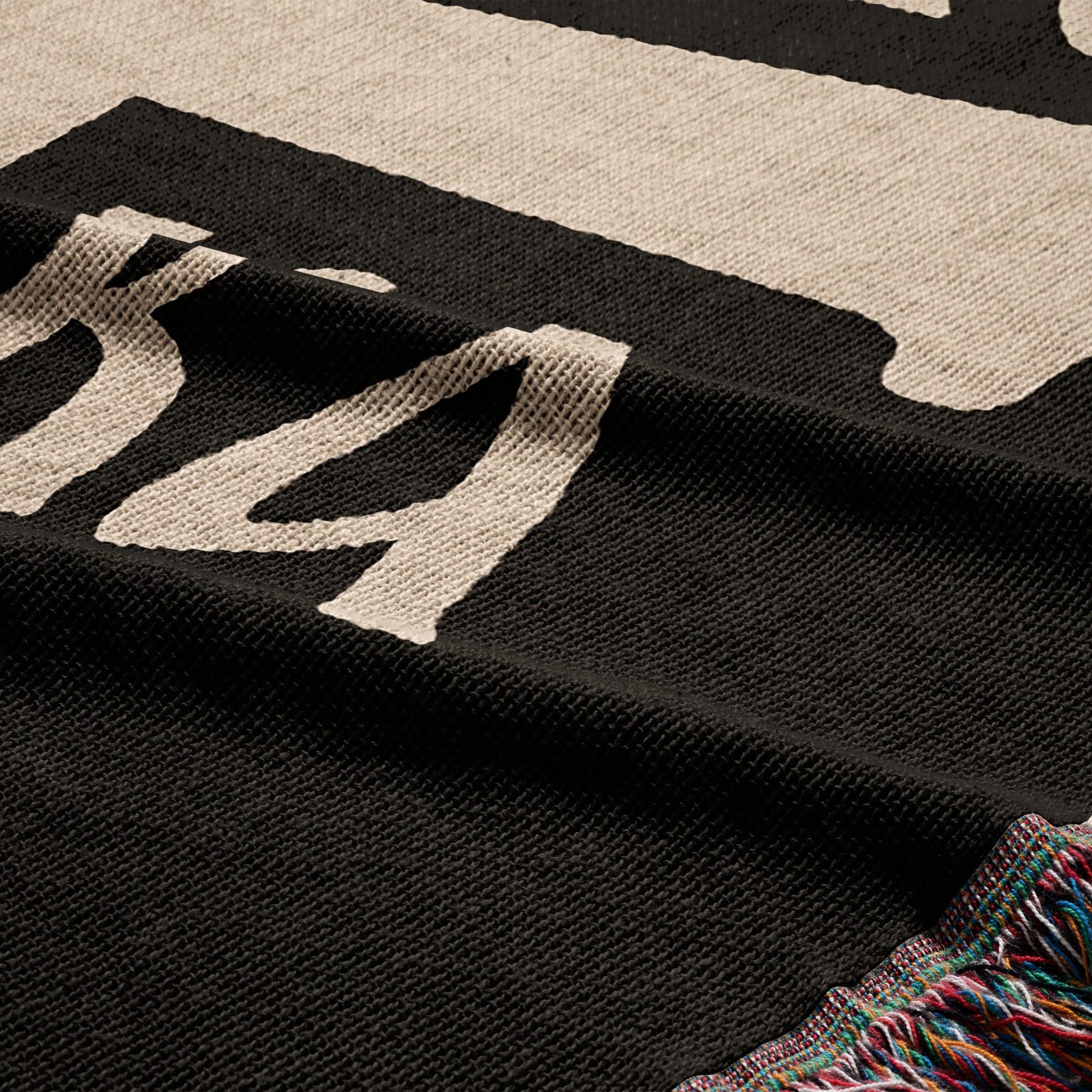 Black and cream knit blanket with fringe, showing partial text.