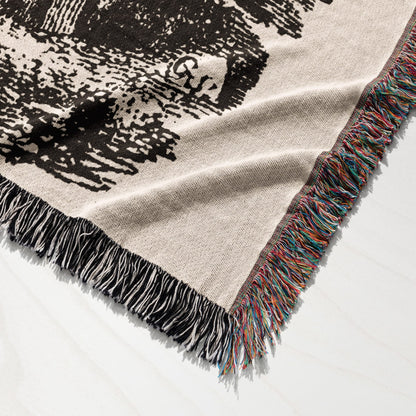 Woven blanket with fringed edges and a detailed black and white graphic design.