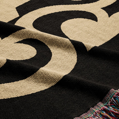 Black blanket with tan swirling pattern and fringed edge.
