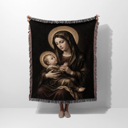 Tapestry depicts Virgin Mary holding baby Jesus, both with halos, against a dark background.