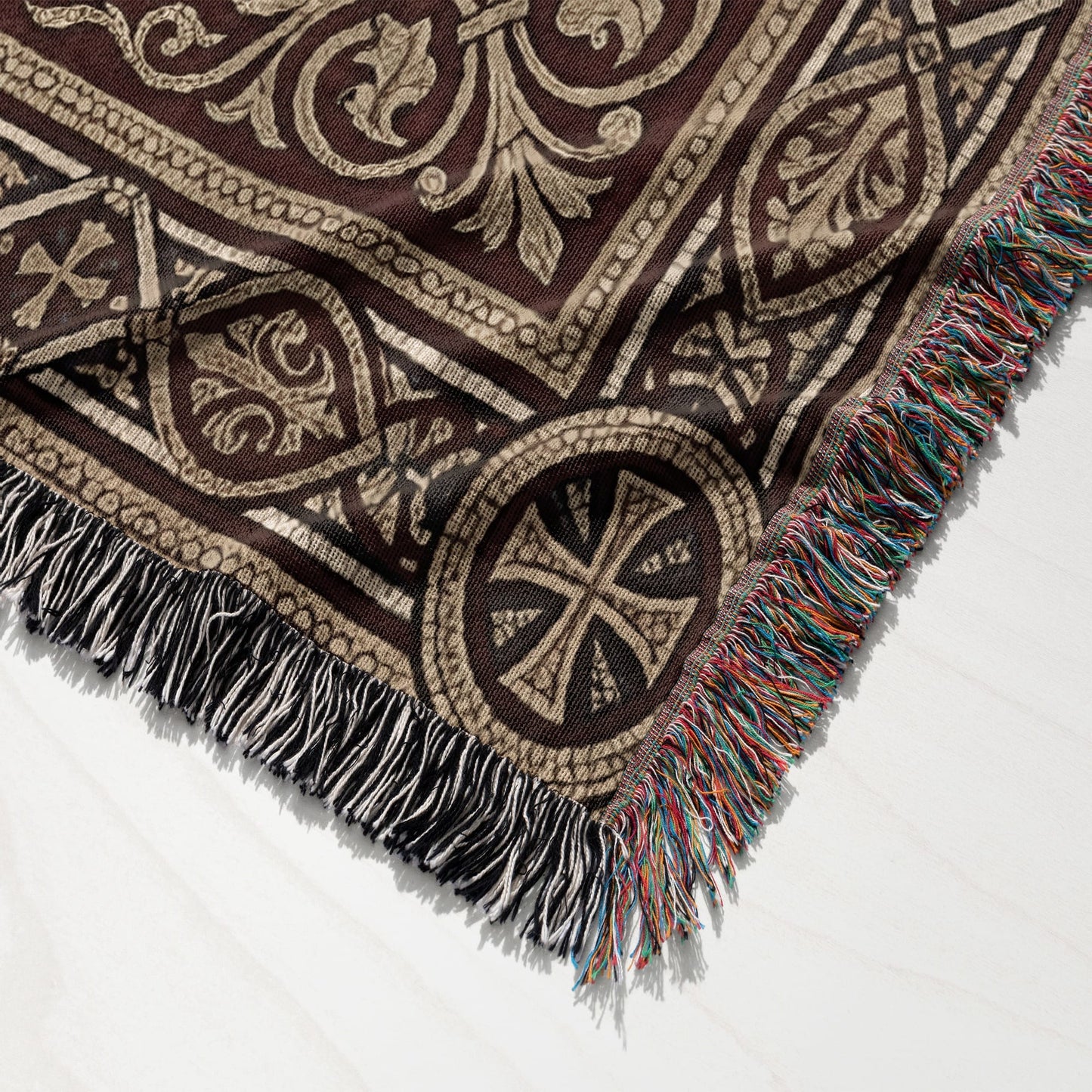 Brown tapestry throw blanket with ornate cross pattern and fringed edges.