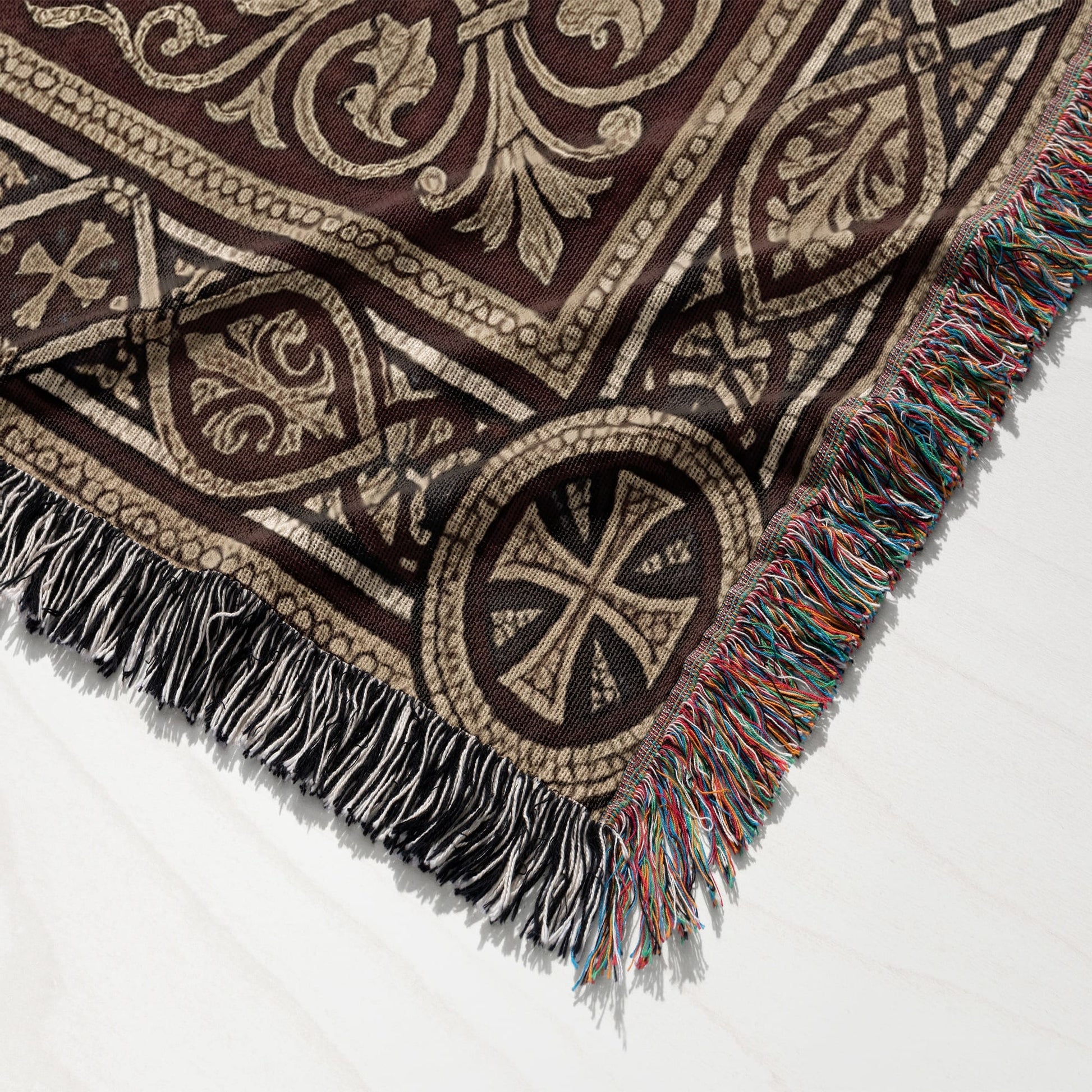 Brown tapestry throw blanket with ornate cross pattern and fringed edges.