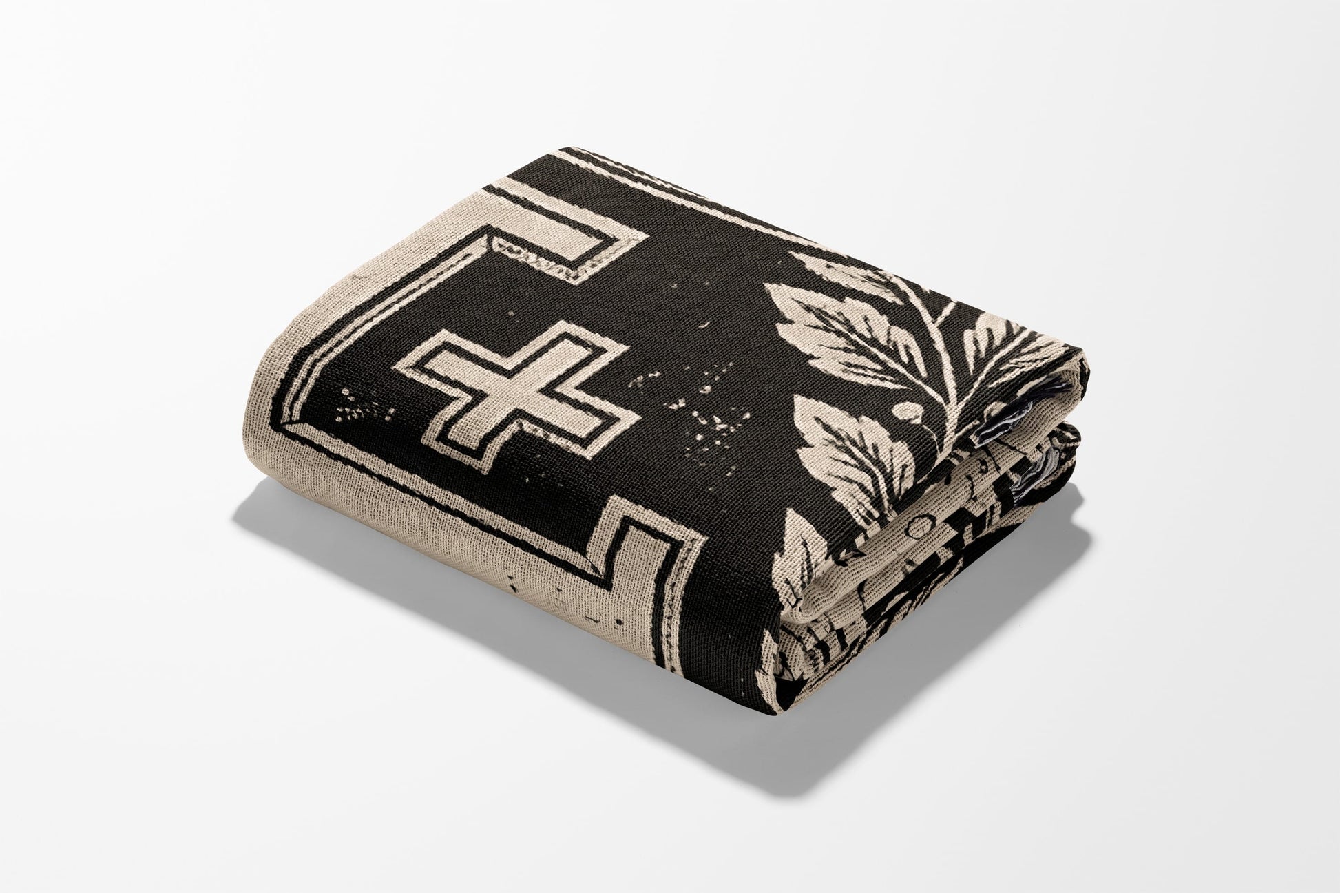 Folded textile with black and beige geometric and floral pattern.
