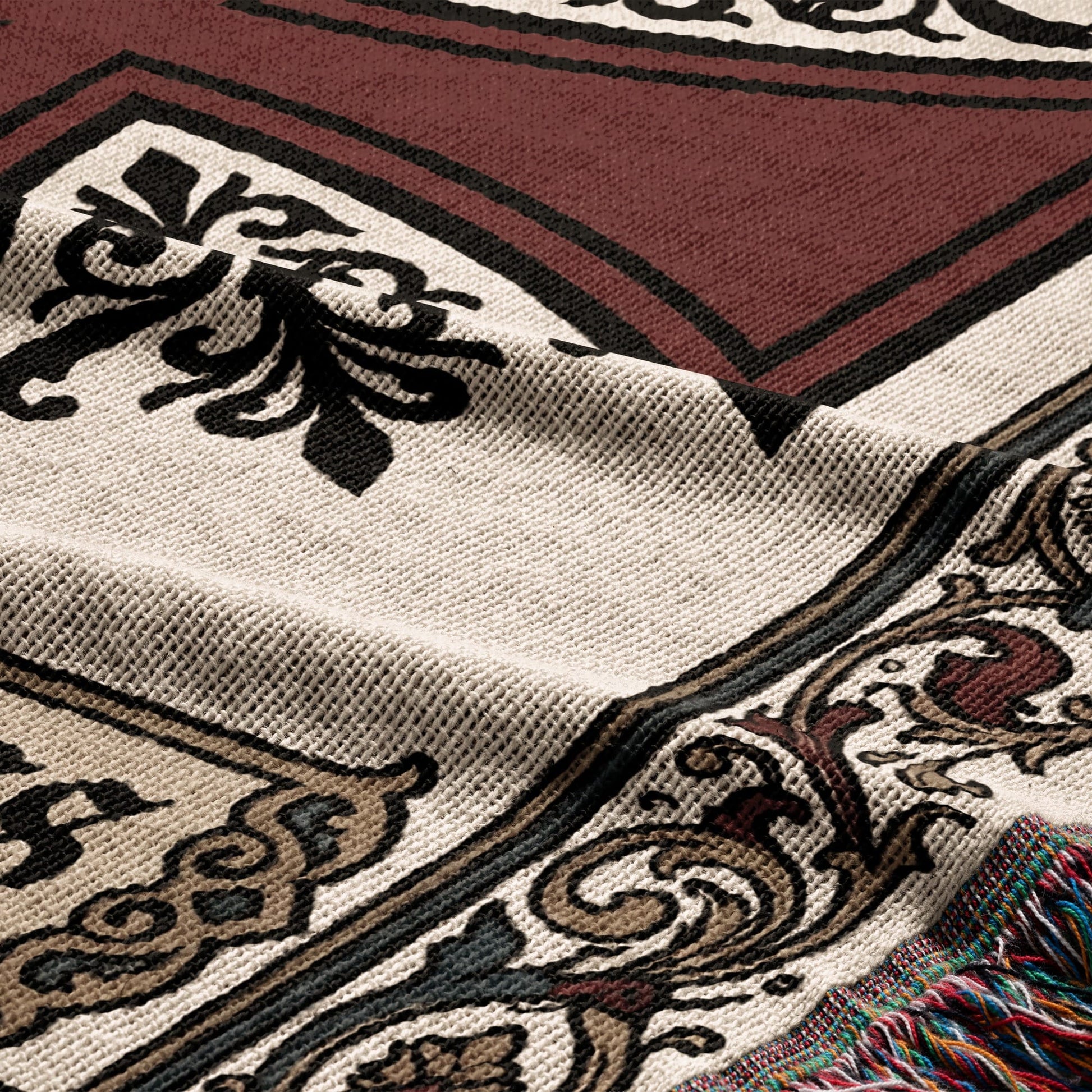 Brown and beige woven throw blanket with ornate black and tan pattern and colorful fringe.