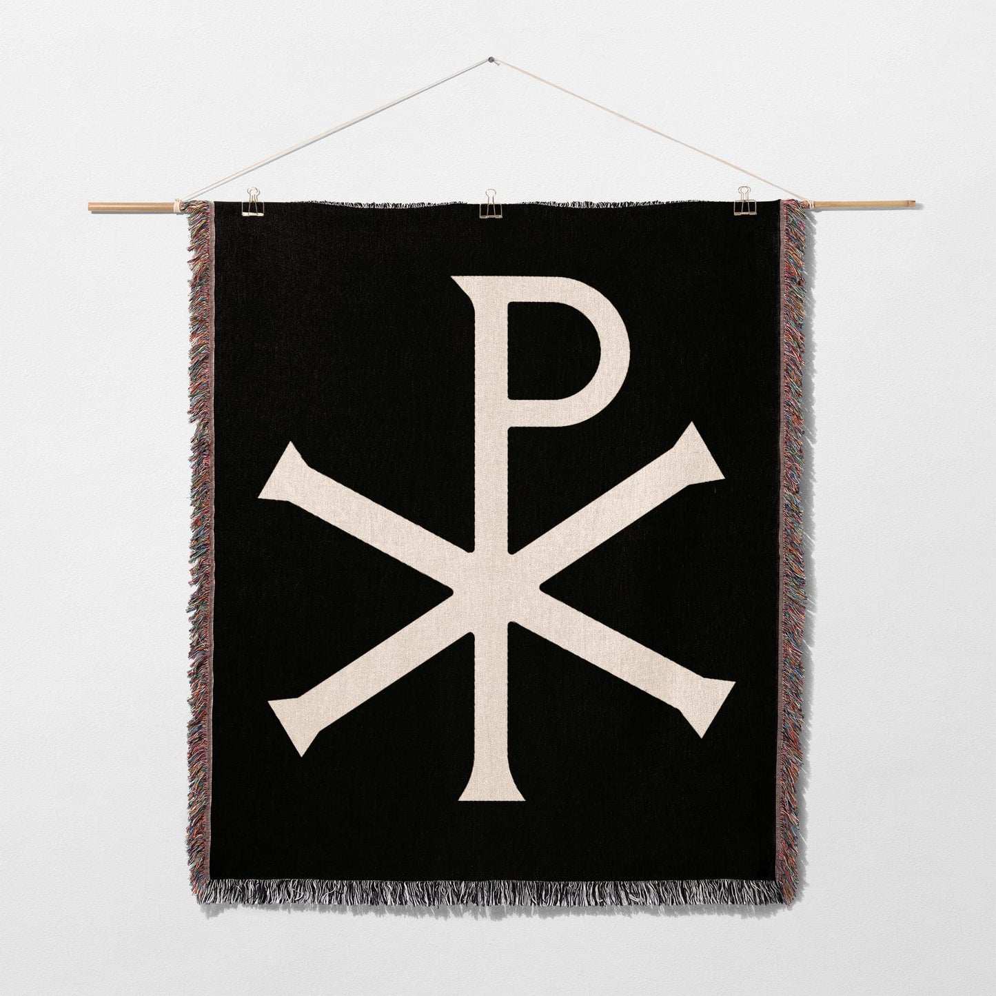Black wall hanging with white Chi Rho symbol and fringe.