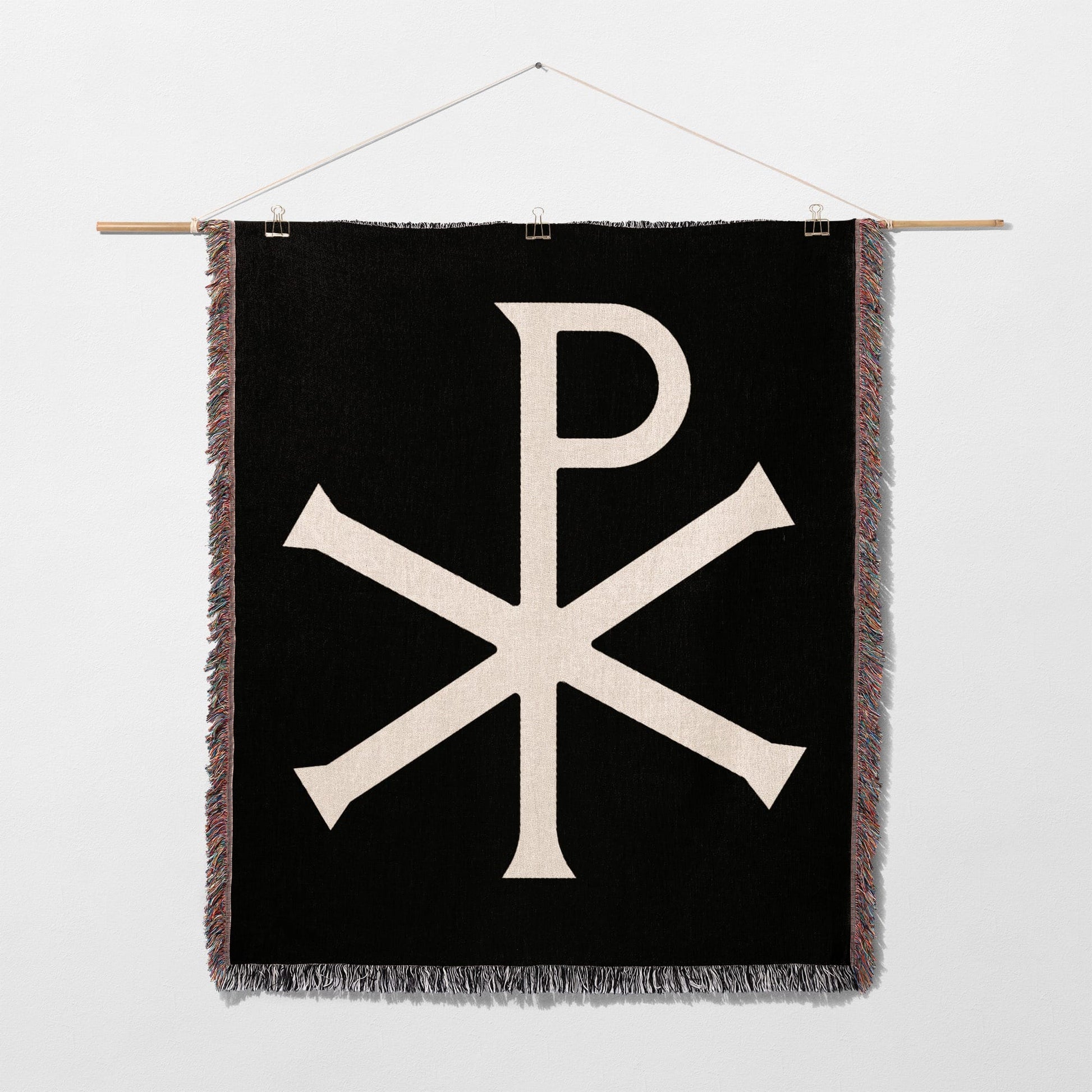 Black wall hanging with white Chi Rho symbol and fringe.
