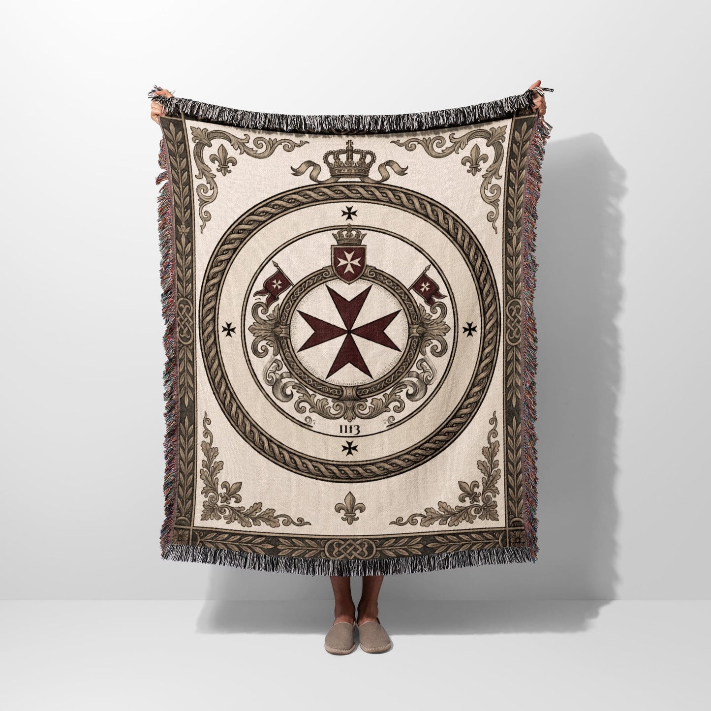Woven blanket with a central circular emblem featuring a cross, crown, and ornate details.