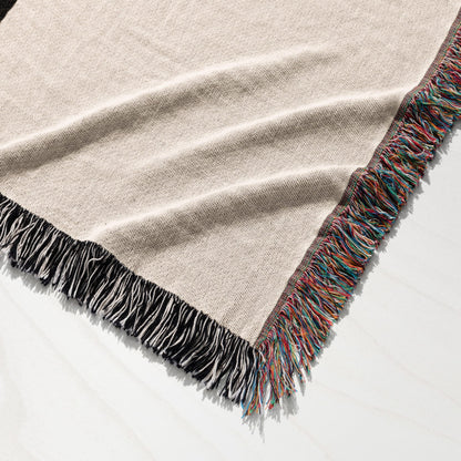 Textured cream woven blanket with colorful fringed edges on white surface.