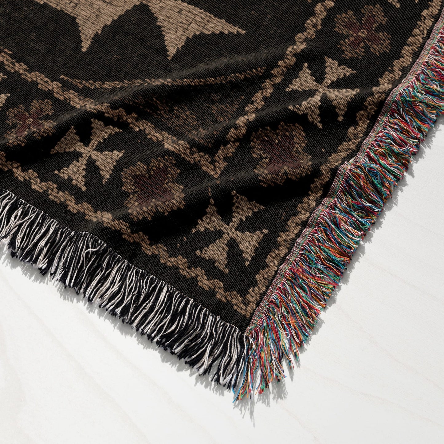 Black throw blanket with fringed edges and a geometric pattern.