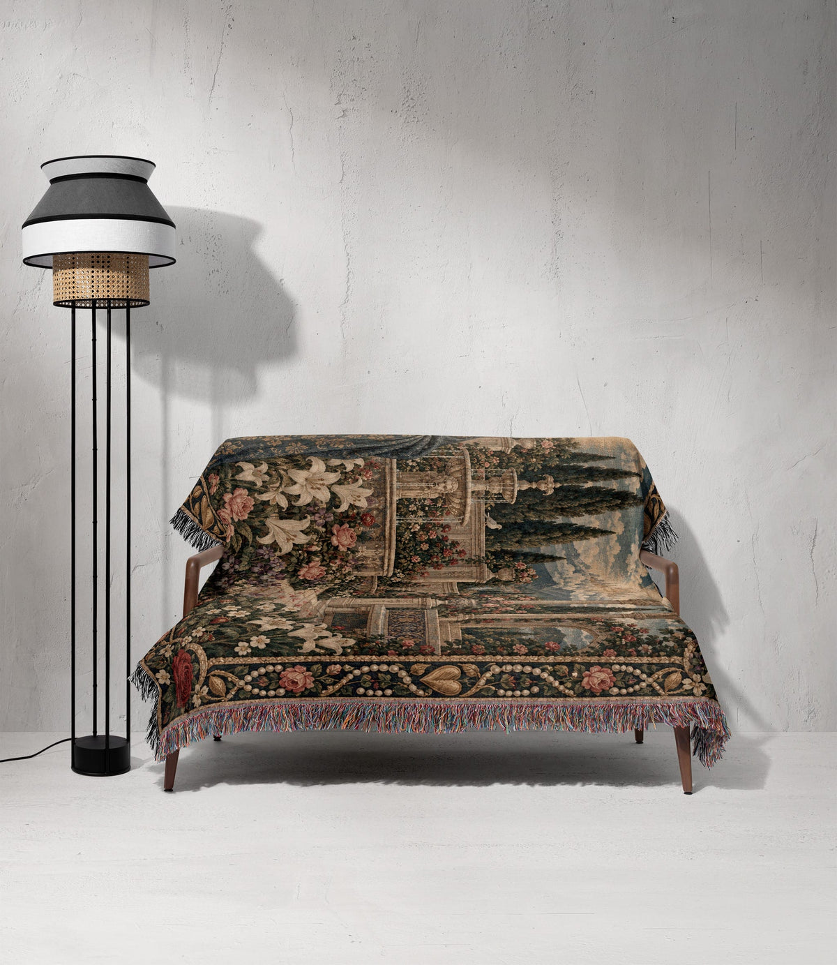 A wooden sofa covered with a decorative tapestry throw blanket beside a modern black floor lamp.