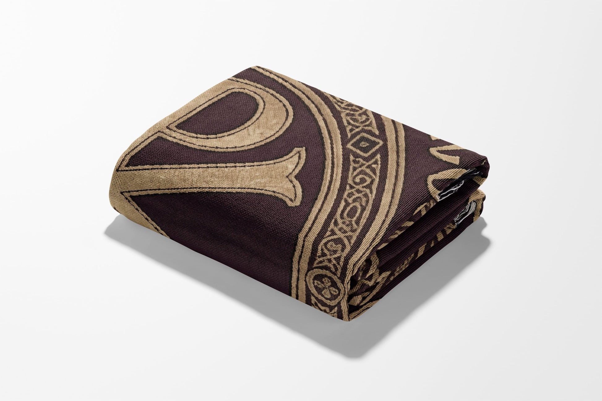 Folded brown blanket with ornate gold pattern.