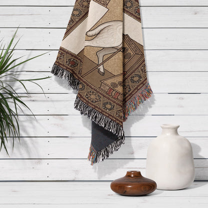 Woven blanket with geometric patterns and sheep motif hanging on a white wooden wall.