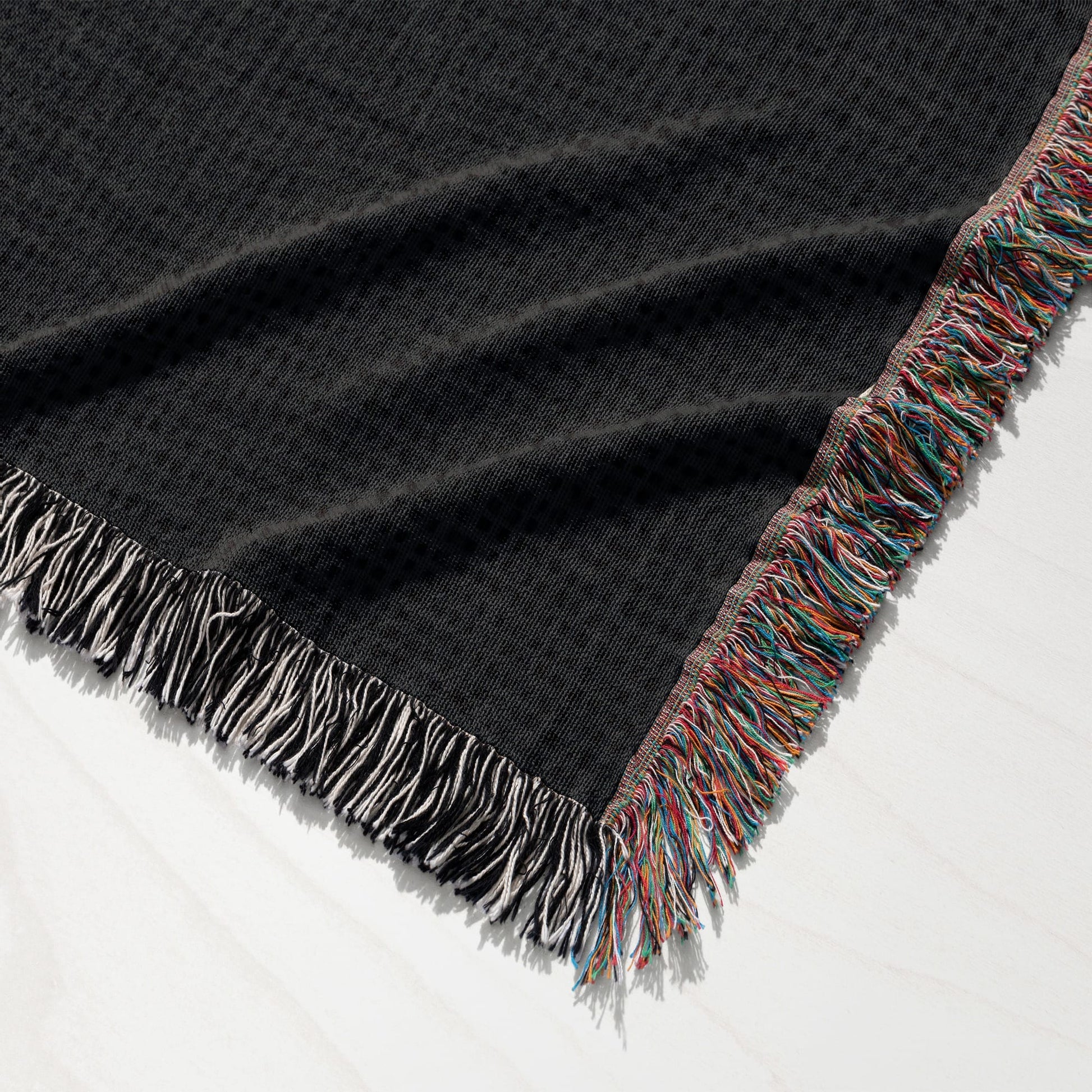 Black woven blanket with fringed edges, showing a detailed texture.