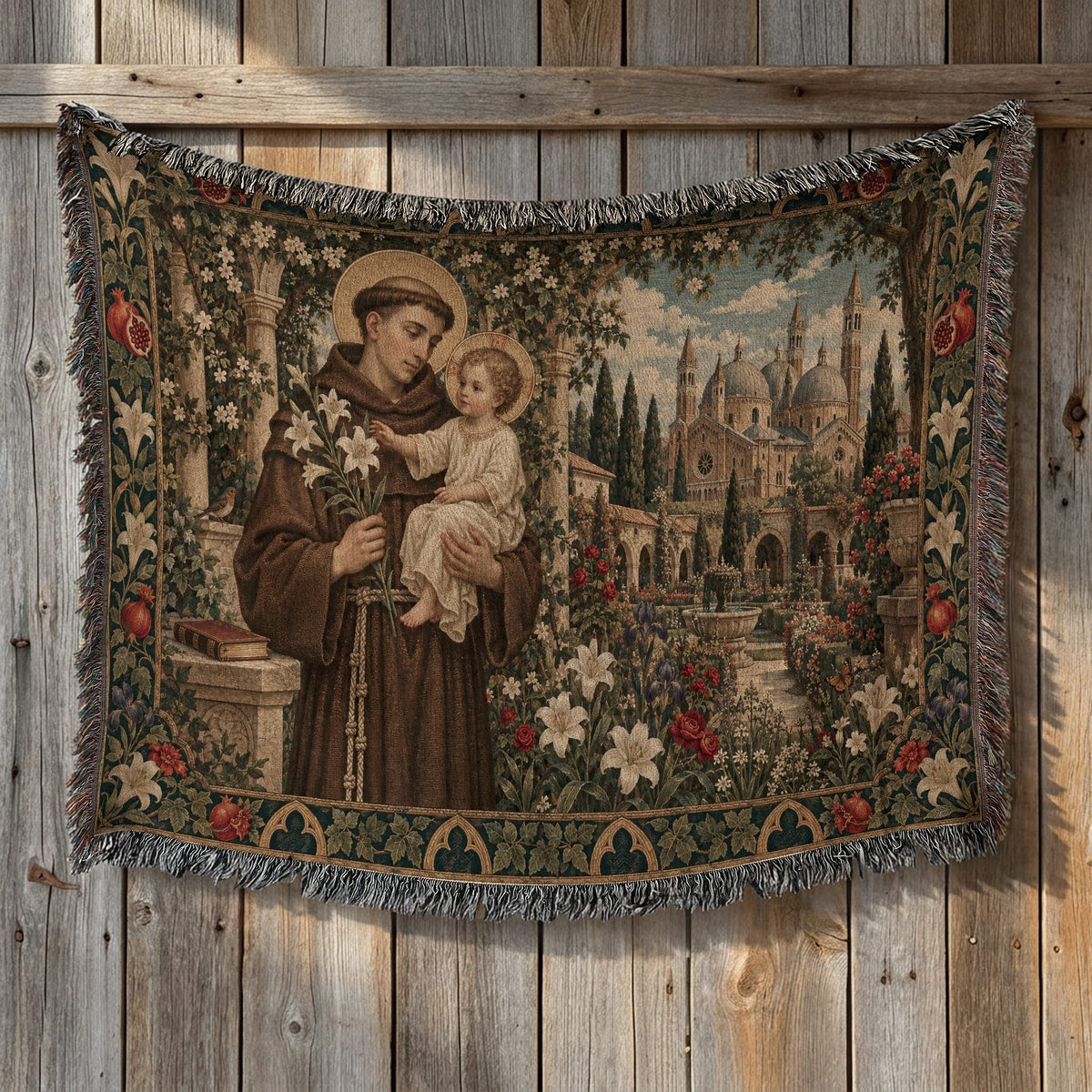 A woven tapestry with fringed edges depicts Saint Anthony holding white lilies and the Christ Child in a garden with a cathedral backdrop.