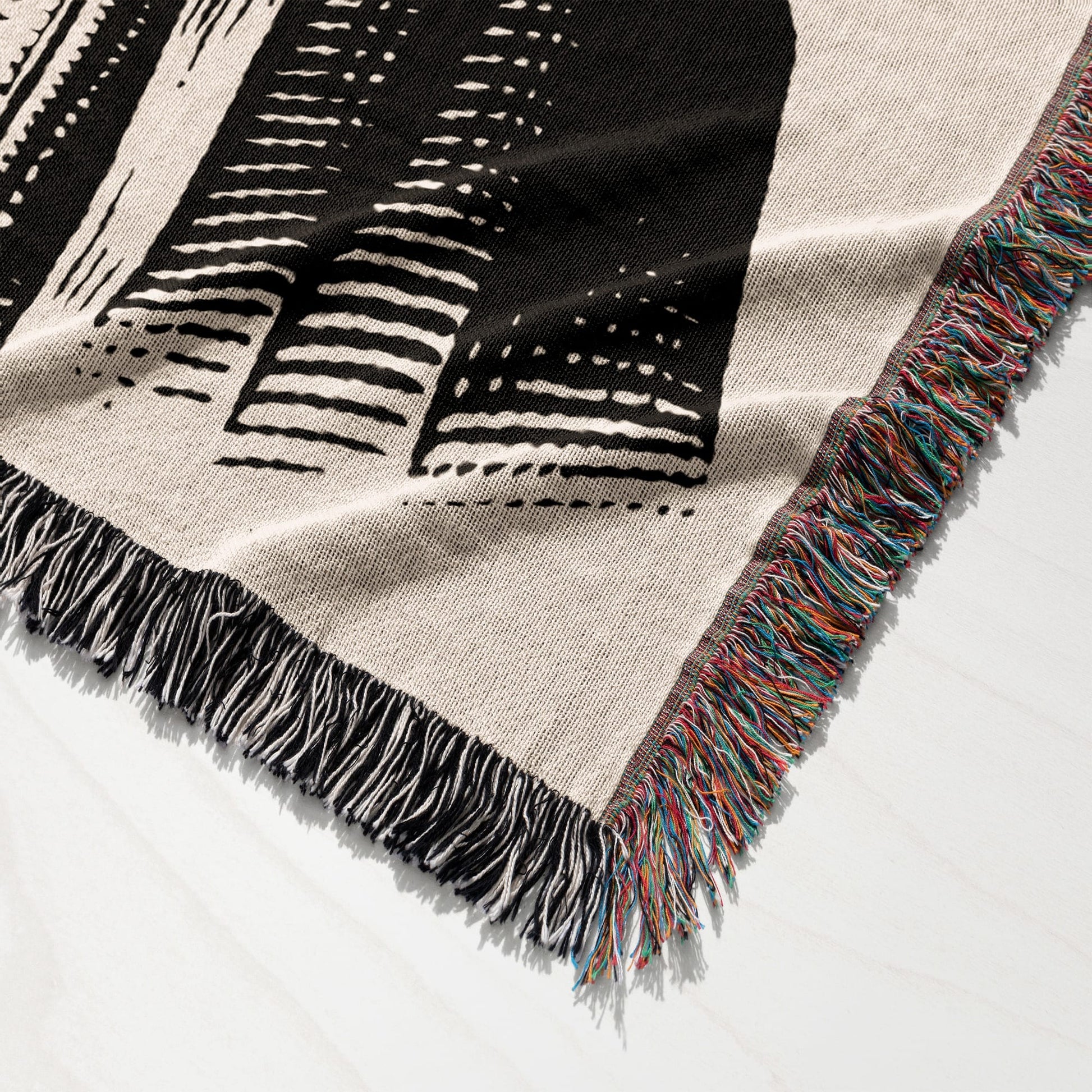 Close-up of a woven blanket with geometric pattern and colorful fringe.