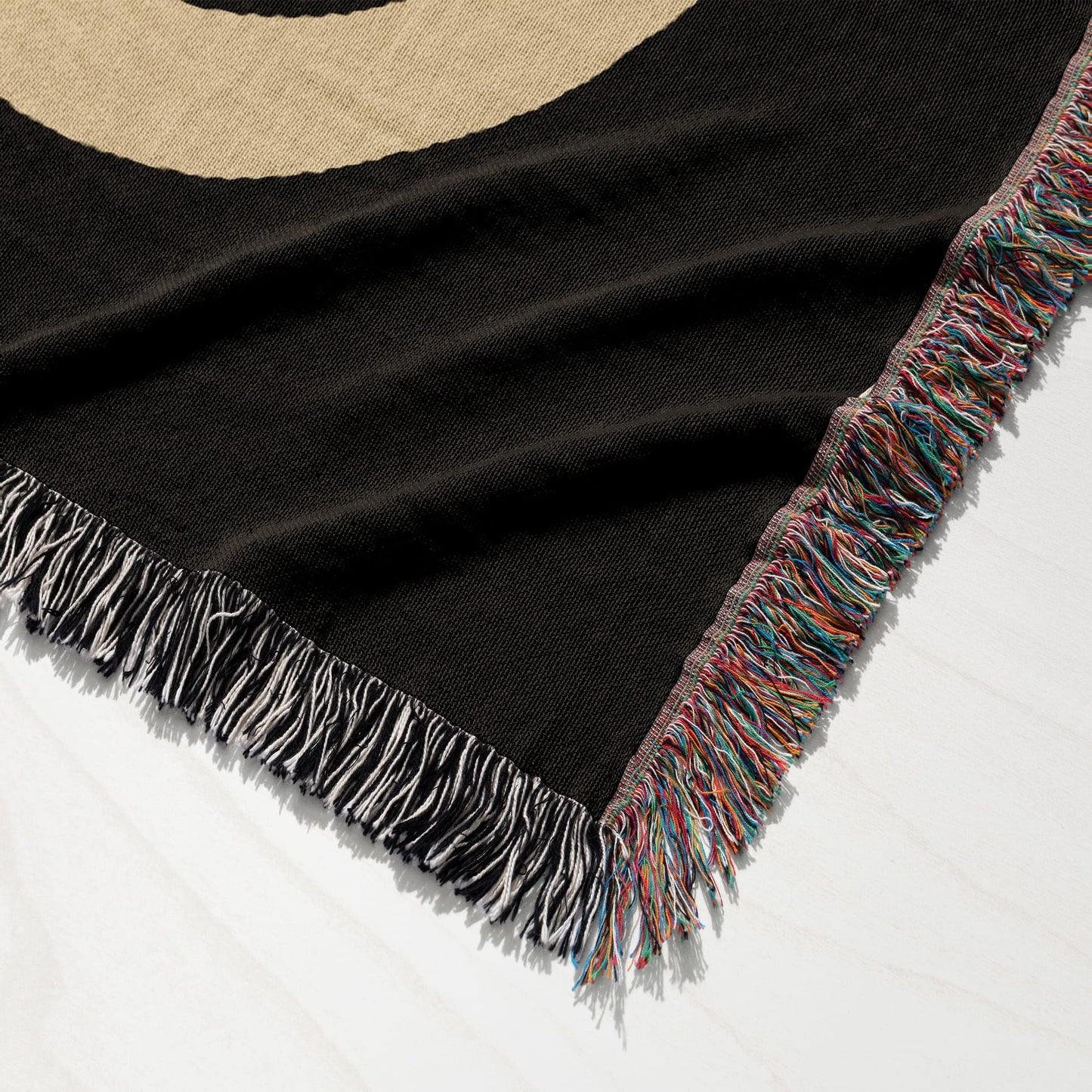 Black throw blanket with colorful fringe, detailed close-up.