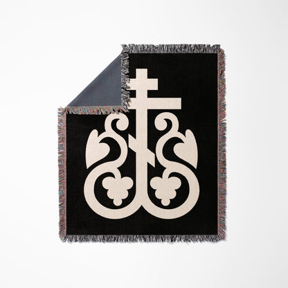 Black blanket with a white Orthodox cross design and colorful fringed edges.