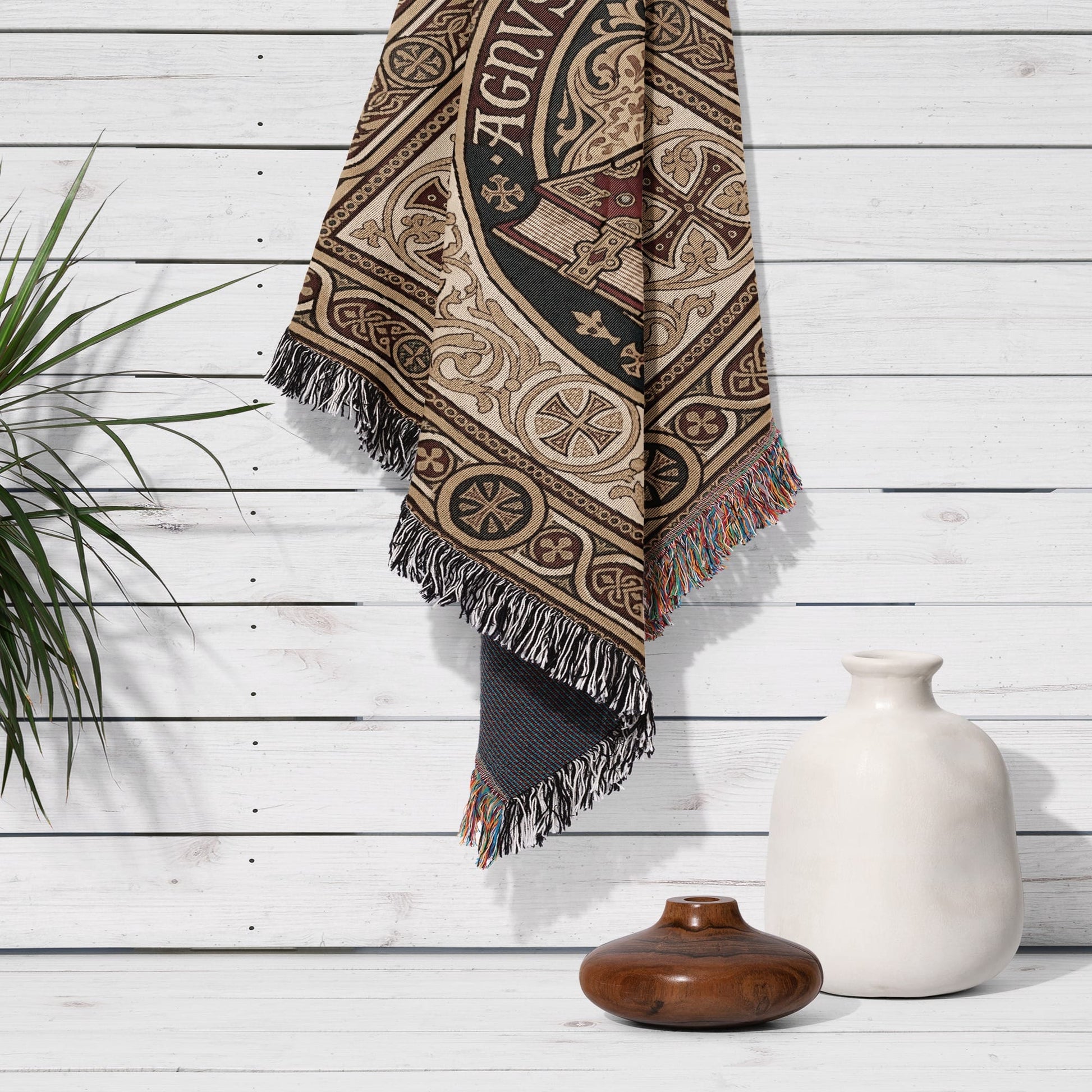 Tapestry with intricate design and fringe hanging on white wooden wall.