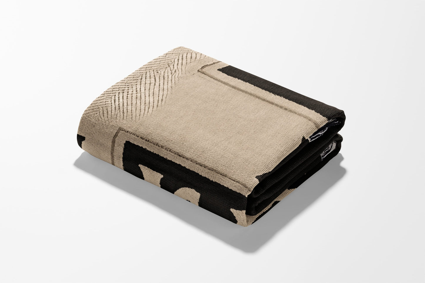 Folded tan and black patterned throw blanket on white background.