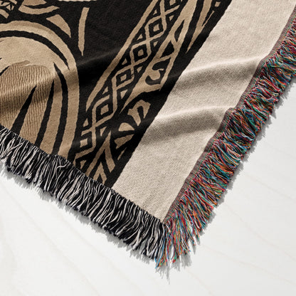 Woven throw blanket with fringe and abstract geometric pattern in tan and black.