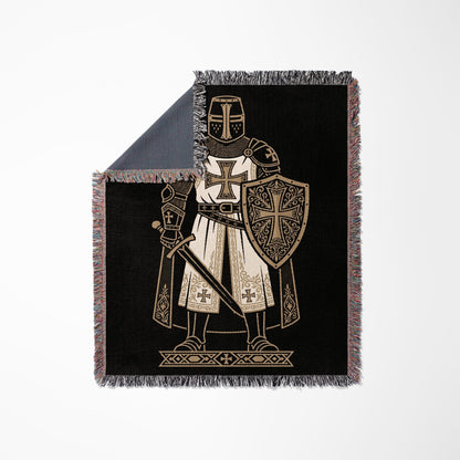 Knight in armor with sword and shield on black blanket.