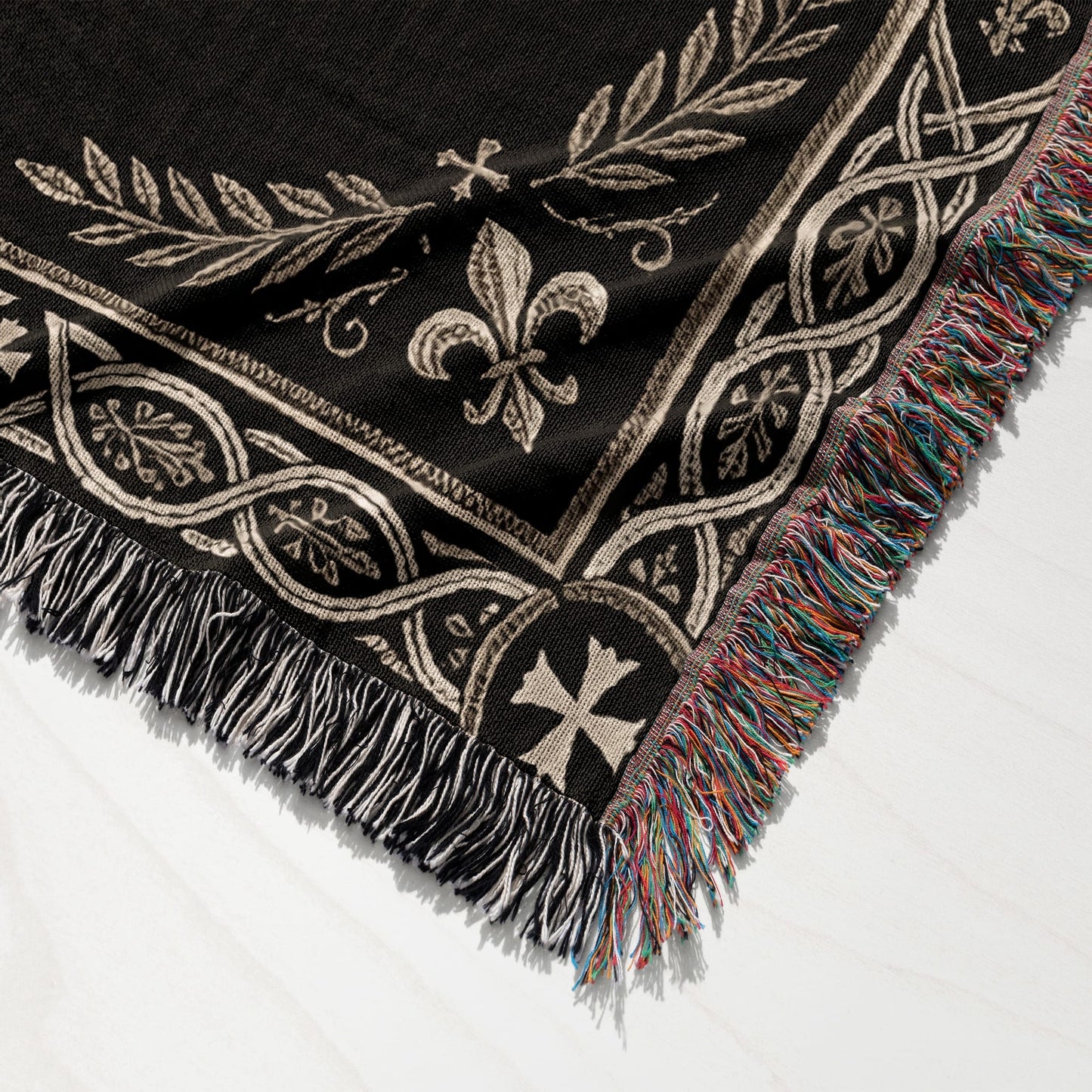 Black woven throw blanket with ornate border featuring fleur-de-lis and crosses.