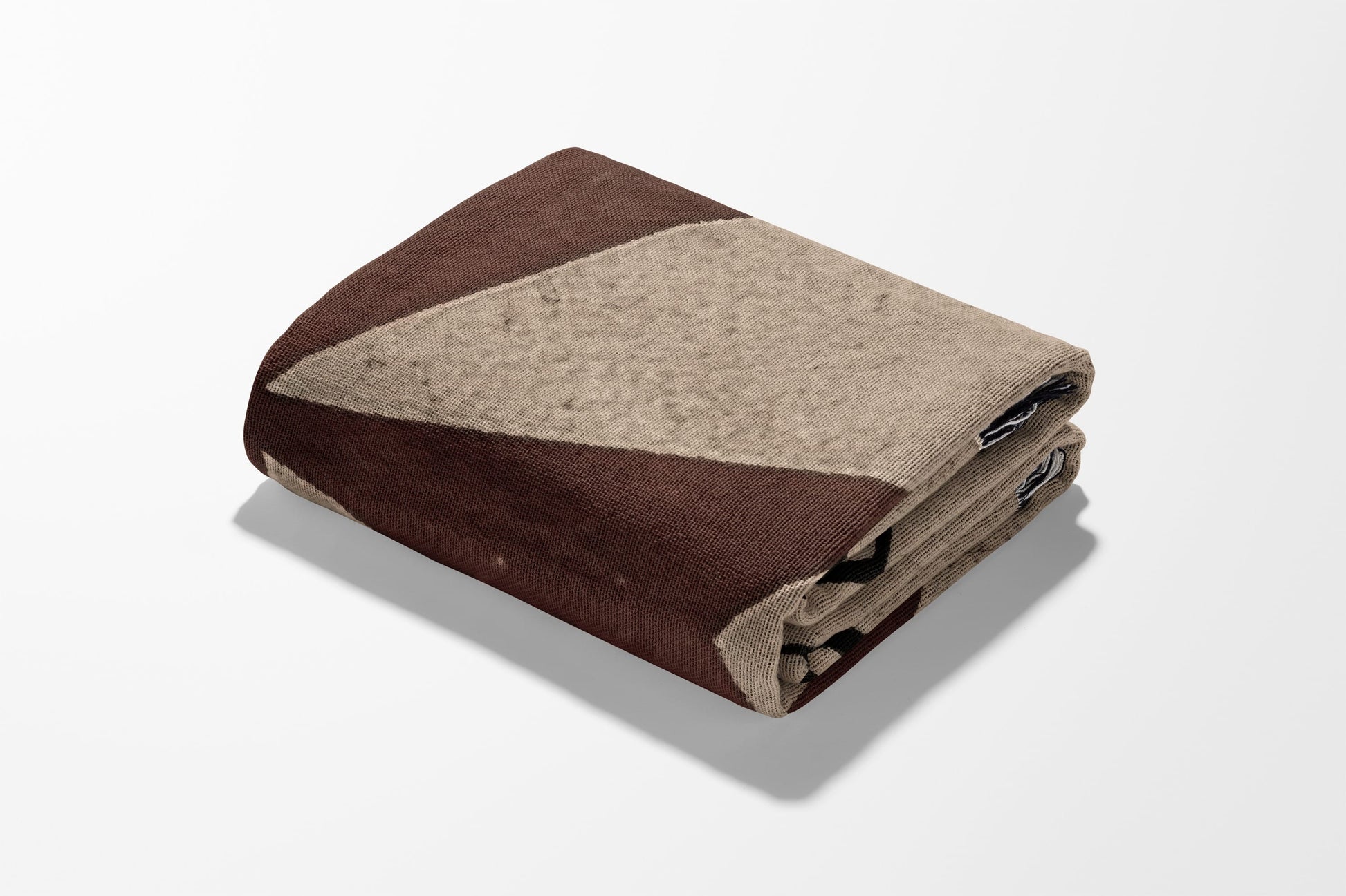 Folded blanket with brown and beige geometric pattern on white background.