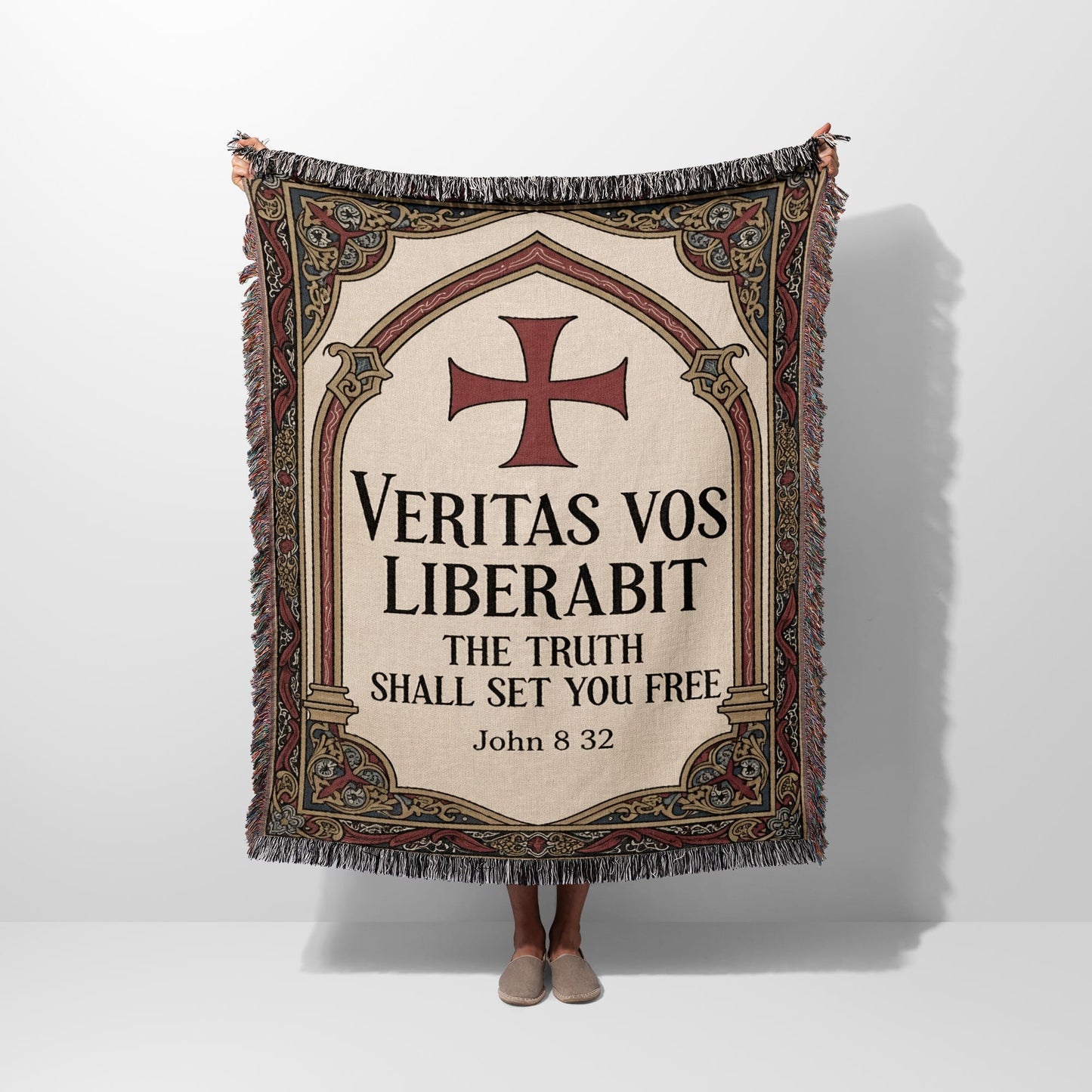 Woven blanket with red cross and "Veritas vos liberabit. The truth shall set you free. John 8:32."