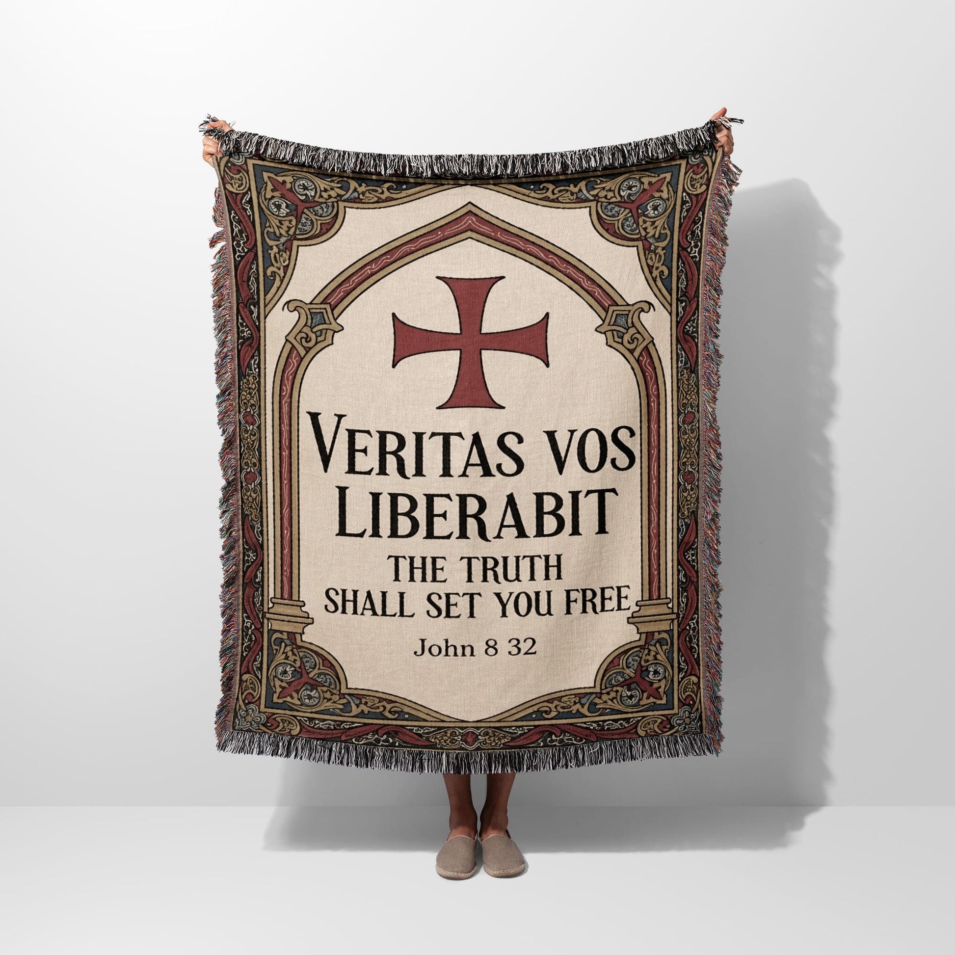 Woven blanket with red cross and "Veritas vos liberabit. The truth shall set you free. John 8:32."