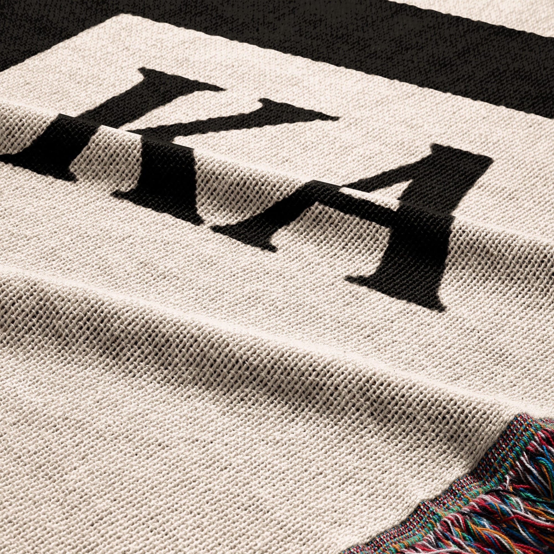 Close-up of a cream and black striped blanket with fringed edge.