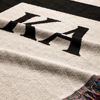 Close-up of a cream and black striped blanket with fringed edge.