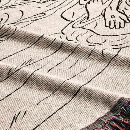 Close-up of a knitted throw blanket with a black line drawing design and a fringed edge.