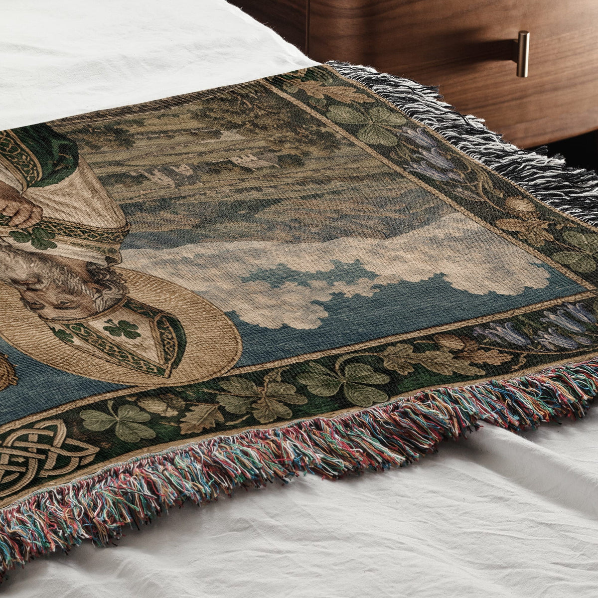 Woven throw blanket featuring a Saint Patrick design, spread across a white bed.